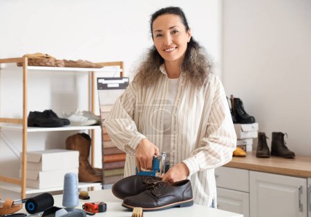 Zapatera mujer reparando bota con pistola de grapas en taller