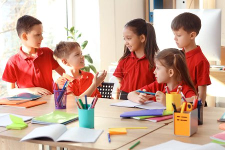 Photo for Cute little pupils studying at table in classroom. School holidays concept - Royalty Free Image