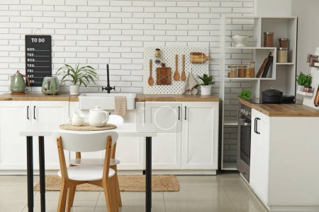 Téléchargez les photos : Élégante cuisine légère avec pegboard et table à manger moderne - en image libre de droit