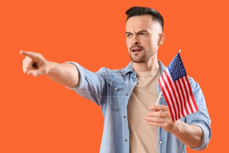 Junger Mann mit USA-Fahne zeigt auf etwas auf orangefarbenem Hintergrund. Anschuldigungskonzept