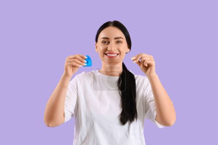 Téléchargez les photos : Belle jeune femme heureuse avec fil dentaire sur fond violet - en image libre de droit