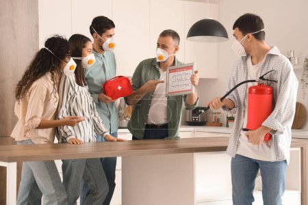 People with evacuation plan, first aid kit and fire extinguisher in burning kitchen