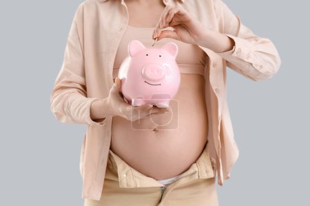 Young pregnant woman putting coin into piggy bank on light background, closeup. Maternity Benefit concept