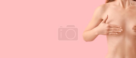 Foto de Mujer joven desnuda tocándose el pecho sobre fondo rosa con espacio para el texto - Imagen libre de derechos