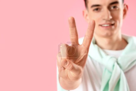 Photo for Young man showing two fingers on pink background, closeup - Royalty Free Image