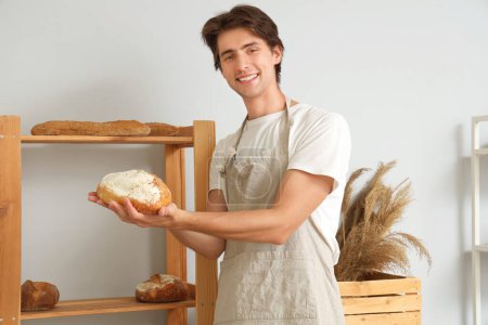 Photo for Handsome young man with loaves of fresh bread in bakery - Royalty Free Image
