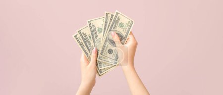 Photo for Female hands holding dollar banknotes on pink background - Royalty Free Image