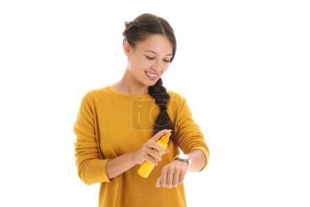 Photo for Beautiful young Asian woman spraying mosquito repellent onto her arm on white background - Royalty Free Image