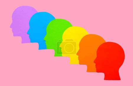 Colorful paper human heads on pink background. LGBTQ concept