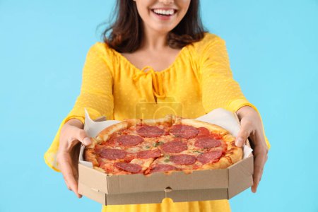 Photo for Young woman with tasty pepperoni pizza on blue background, closeup - Royalty Free Image