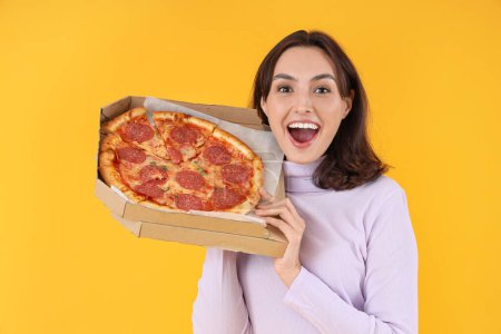 Young woman with tasty pepperoni pizza on yellow background