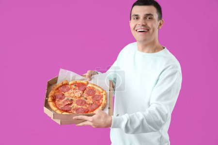 Junger Mann mit leckerer Pfefferoni-Pizza auf lila Hintergrund