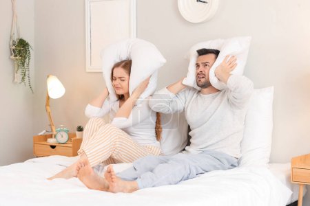 Junges Paar mit Kopfkissen leidet unter lauten Nachbarn im Schlafzimmer