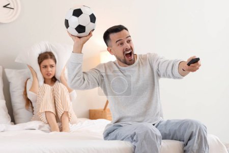 Joven hombre viendo el partido de fútbol y su esposa sufriendo de ruido en el dormitorio