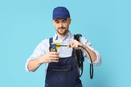 Foto de Retrato de electricista masculino con crimper y alambre sobre fondo azul - Imagen libre de derechos