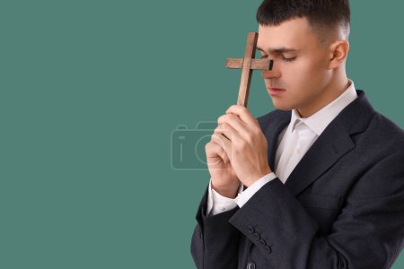 Foto de Joven con cruz de madera rezando sobre fondo verde - Imagen libre de derechos
