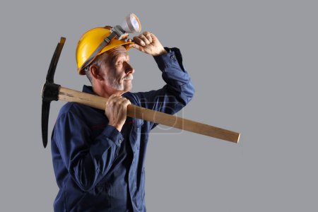 Photo for Mature miner man with pick axe on grey background - Royalty Free Image