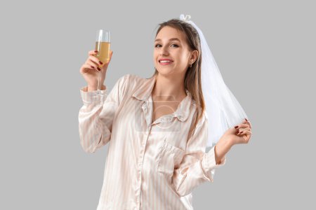 Happy bride in pajamas with champagne on light background. Hen Party