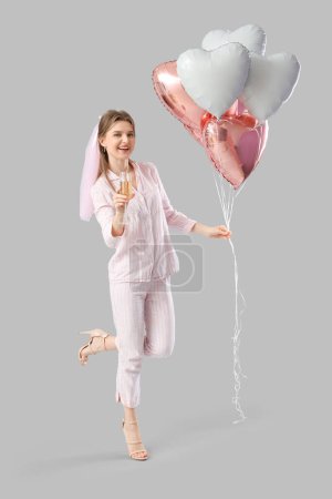 Happy bridesmaid in pajamas with champagne and balloons on light background. Hen Party
