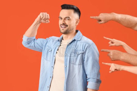 Photo for People pointing at smiling young man on orange background. Accusation concept - Royalty Free Image
