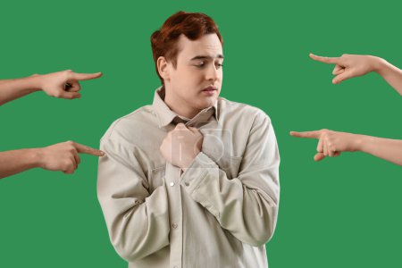 People pointing at shamed young man on green background. Accusation concept