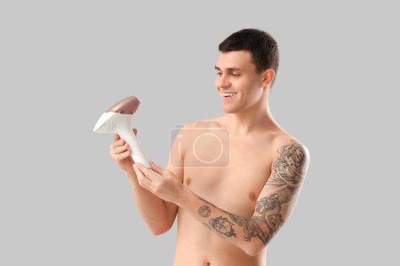 Photo for Young man with photoepilator on grey background - Royalty Free Image