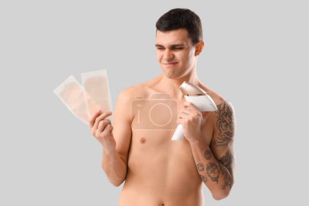 Photo for Young man choosing between photoepilation and waxing on grey background - Royalty Free Image