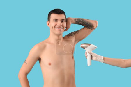 Photo for Cosmetologist using photoepilator for removal of hair from man's body on blue background - Royalty Free Image