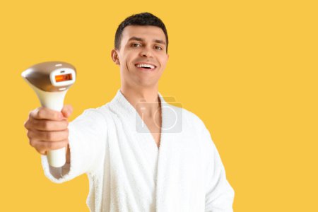 Photo for Young man with photoepilator on yellow background - Royalty Free Image