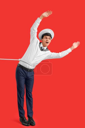 Photo for Young sailor with rope on red background - Royalty Free Image