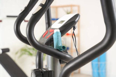 Asthma inhaler on exercise bike in gym, closeup
