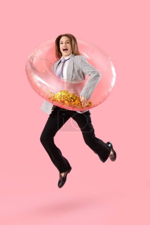 Foto de Joven empresaria divertida con anillo inflable saltando sobre fondo rosa - Imagen libre de derechos