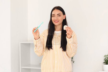 Téléchargez les photos : Belle jeune femme heureuse avec fil dentaire et brosse à dents dans la salle de bain à la maison - en image libre de droit