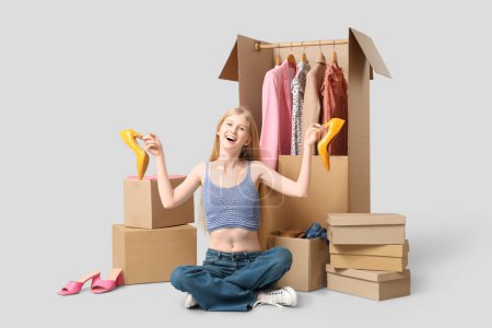 Foto de Hermosa joven feliz mujer con tacones altos y cajas de armario de ropa sobre fondo gris - Imagen libre de derechos
