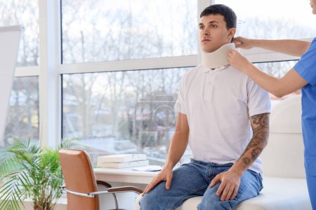 Injured young man after accident applying cervical collar in clinic