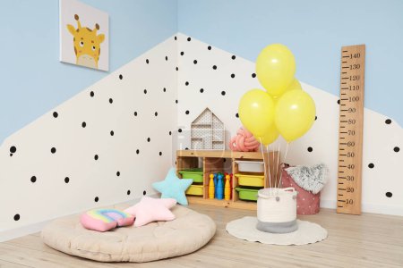 Interior of children's room with bunch of balloons, wooden stadiometer and toys