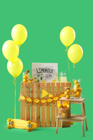 Lemonade stand with balloons and stool on green background