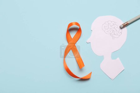 Paper human head with orange ribbon on blue background. Multiple Sclerosis Awareness Month
