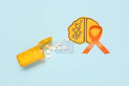 Paper brain with jar of pills and orange ribbon on blue background. Multiple Sclerosis Awareness Month