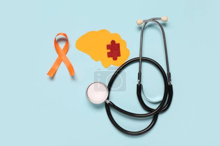Paper brain with puzzle piece, stethoscope and orange ribbon on blue background. Multiple Sclerosis Awareness Month