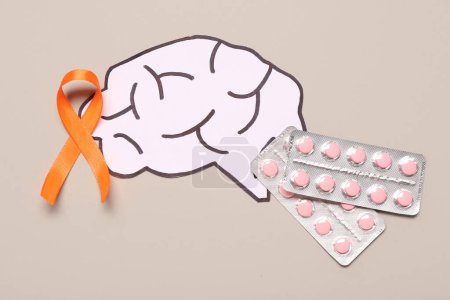Orange ribbon, paper brain and pills on grey background. Multiple Sclerosis Awareness Month