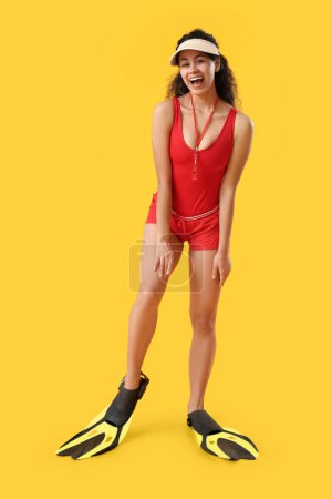 Photo for Beautiful young happy African-American female lifeguard with flippers on yellow background - Royalty Free Image