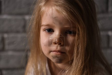 Photo for Homeless little girl near grey brick wall, closeup - Royalty Free Image