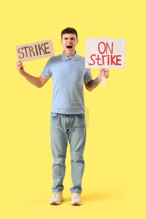 Photo for Protesting young man with placards on yellow background. Strike concept - Royalty Free Image