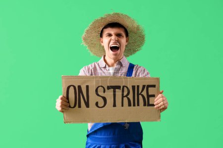 Protestando a un agricultor masculino sosteniendo pancarta con texto SOBRE STRIKE contra fondo verde