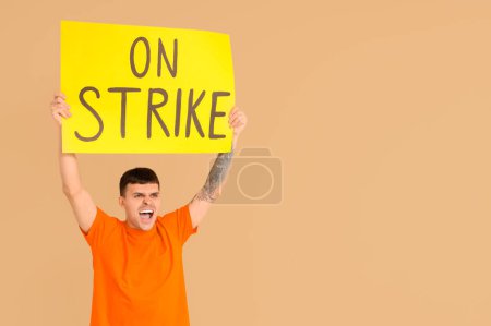 Photo for Protesting young man holding placard with text ON STRIKE against beige background - Royalty Free Image
