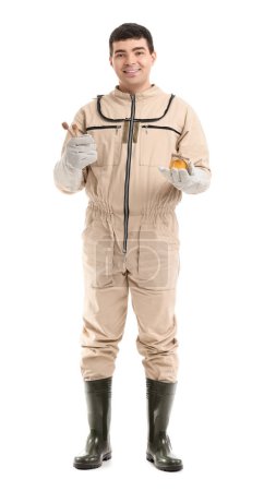 Male beekeeper with honey and spoons on white background