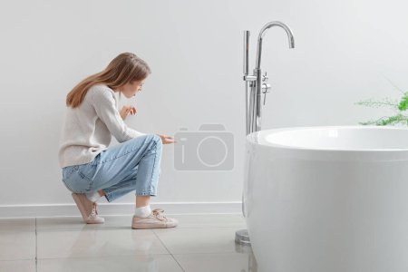 Mujer joven mirando moho en la pared en el baño