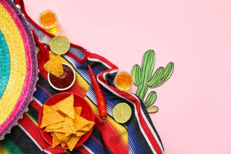 Shots of tequila, nachos and slices of lime on pink background