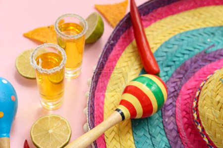 Shots of tequila and sombrero hat on pink background